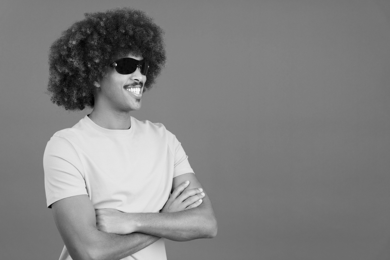 Smiley masculine person wearing sunglasses posing with arms crossed