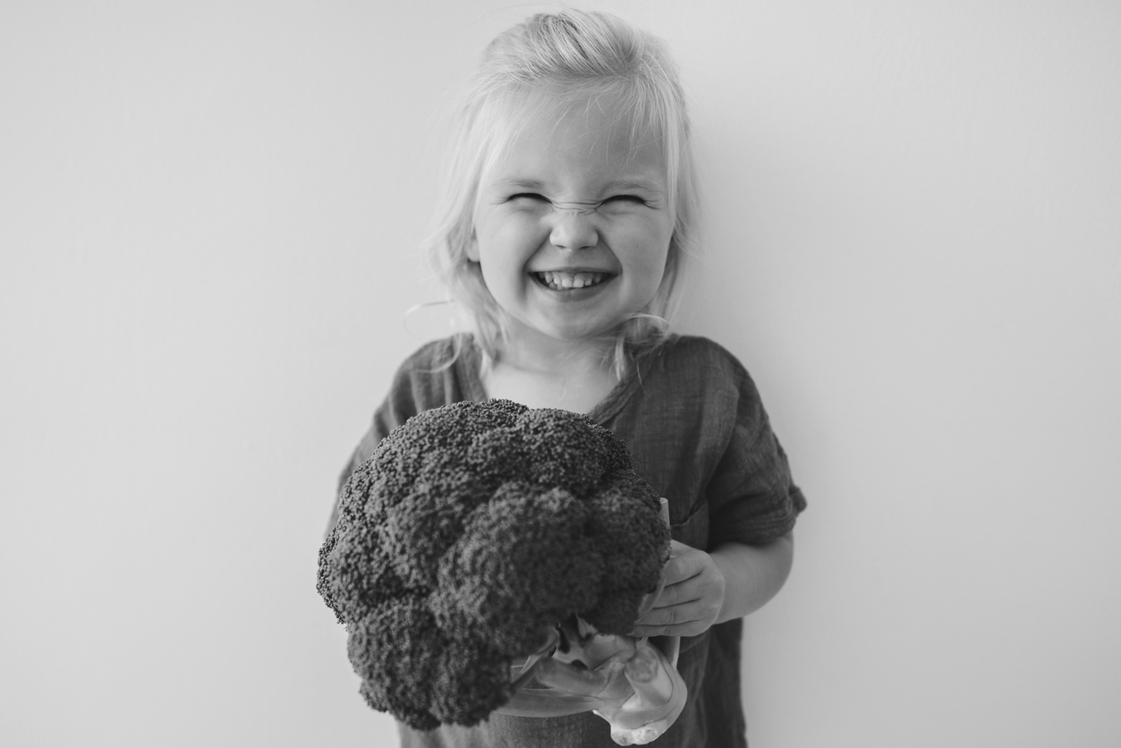 Child holds a huge head of broccoli