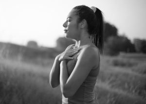 Young person practicing breathing yoga in a field at sunset