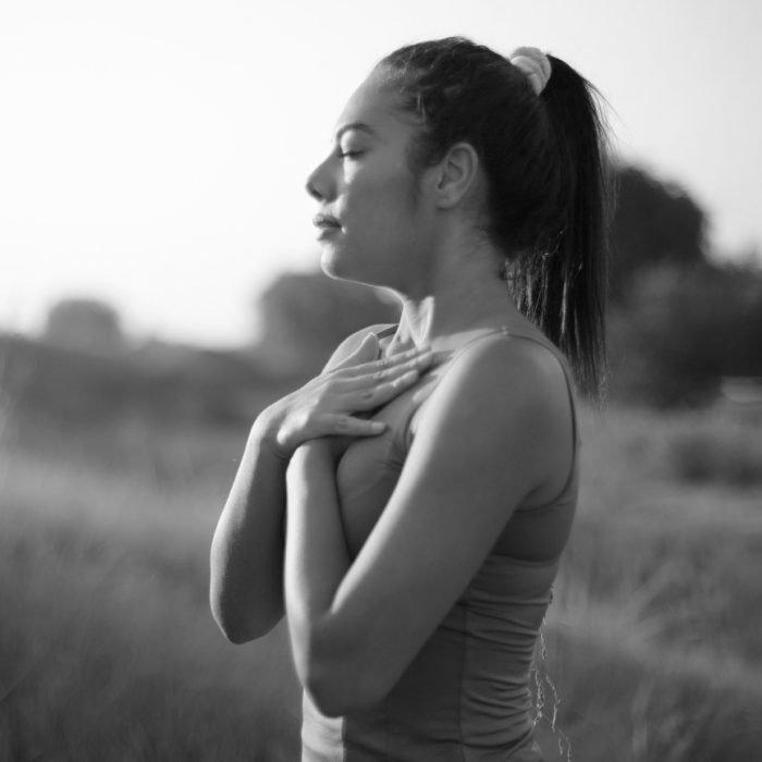 Young person practicing breathing yoga in a field at sunset