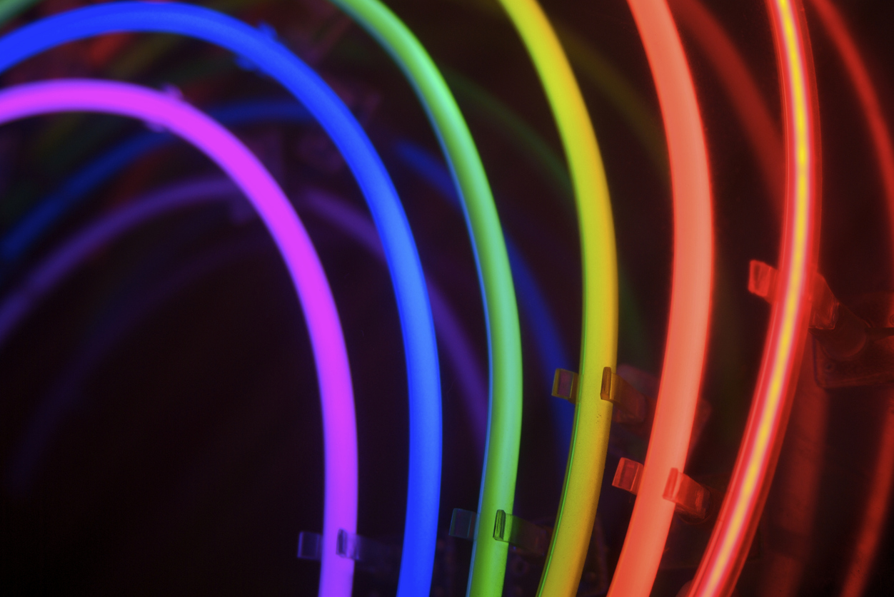 Rainbow of neon stretches over dark copy space