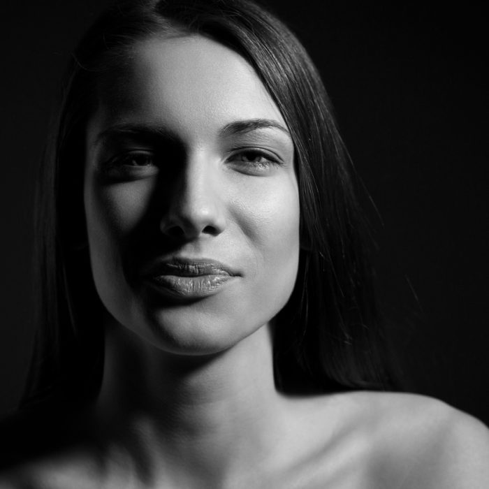 Portrait of brunette person with natural look and without makeup on black background