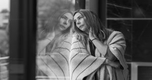 Burnout image of an adult leaning against a window, looking outside