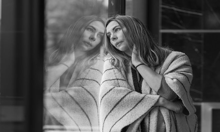 Burnout image of an adult leaning against a window, looking outside
