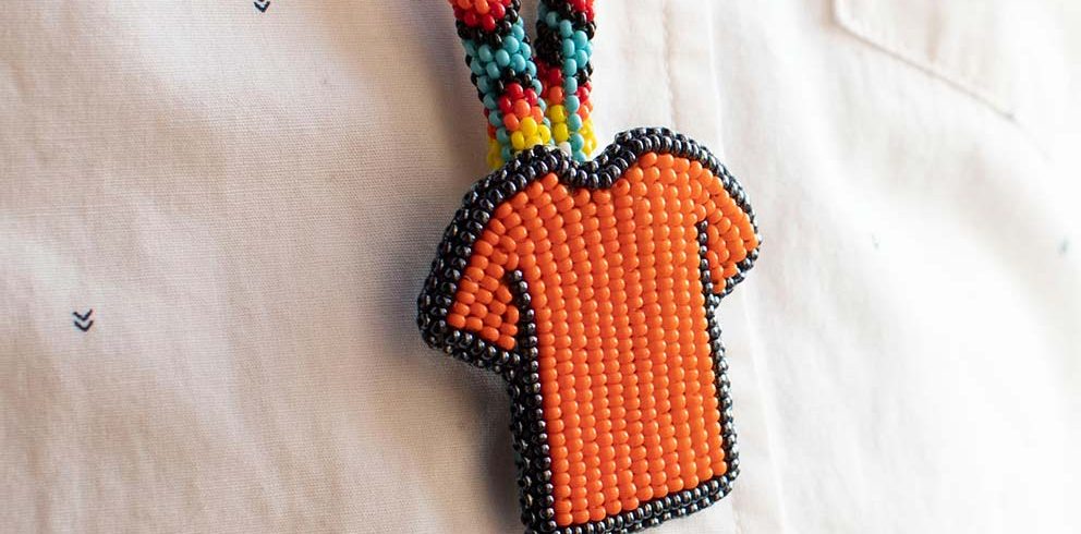 A beaded orange shirt rests on a white background for National Day of Truth and Reconciliation in Canada